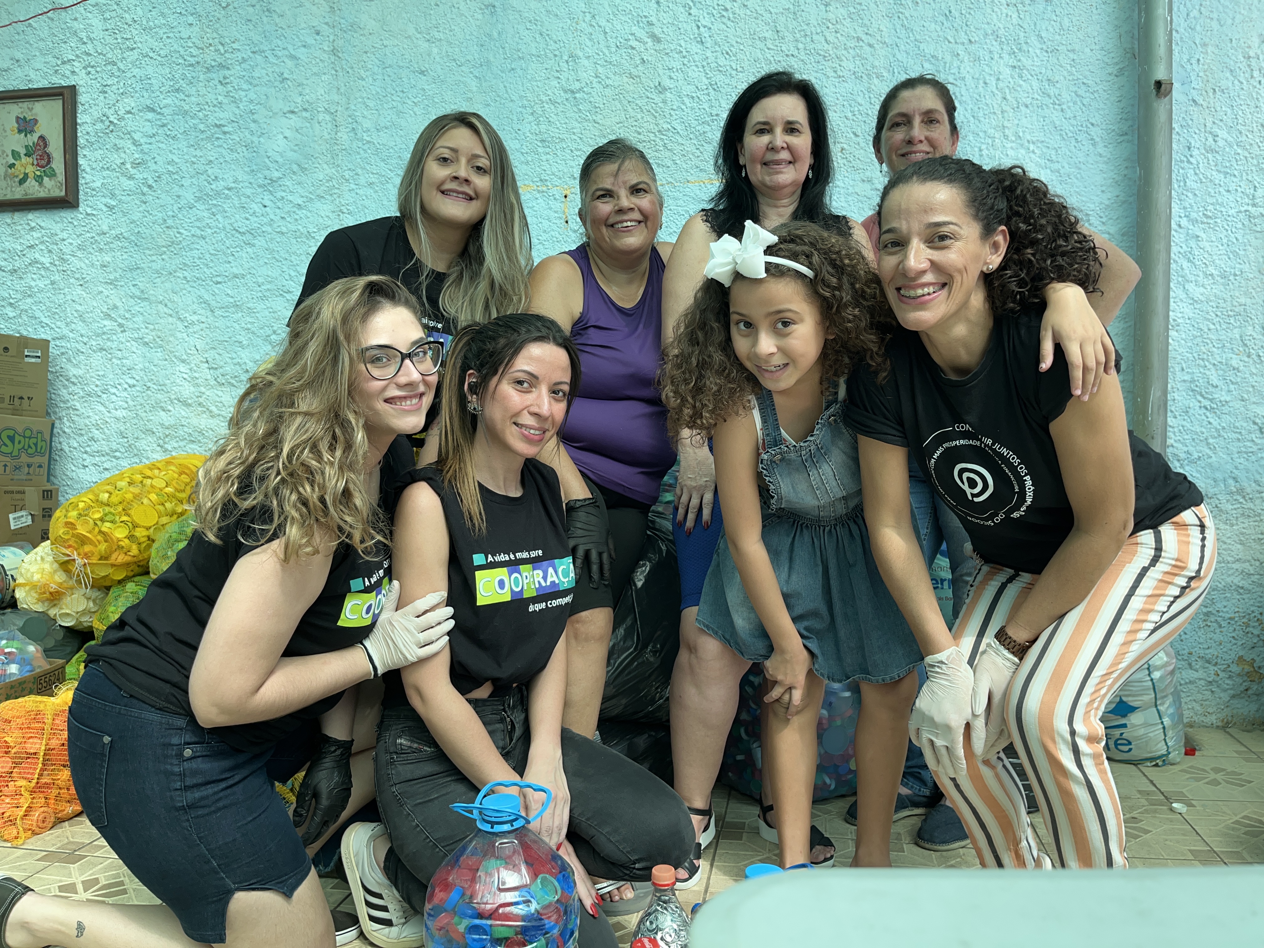 voluntárias unidas na foto com as sacolas de tampinhas atrás.