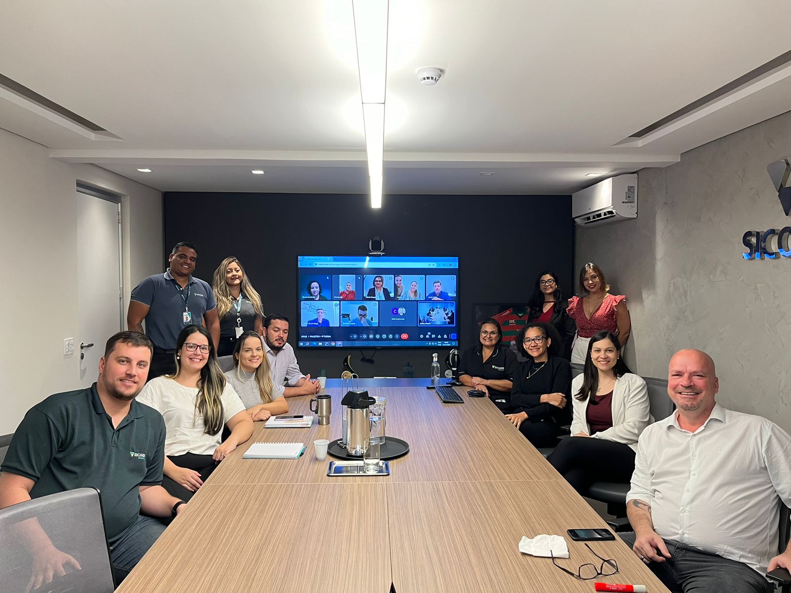 funcionários do Sicoob Metalcred reunidos na sala de reunião. 